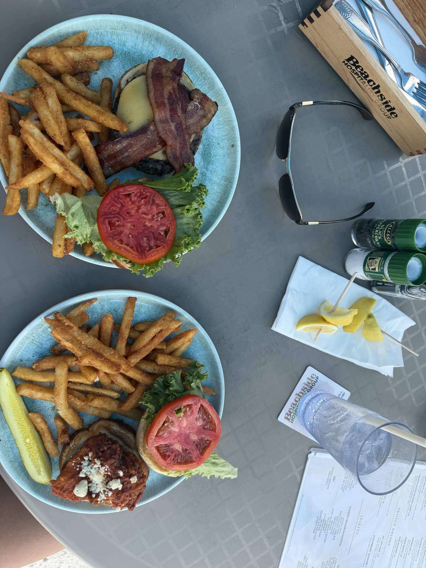 Sandbar burgers and fries on blue plates at beachside table