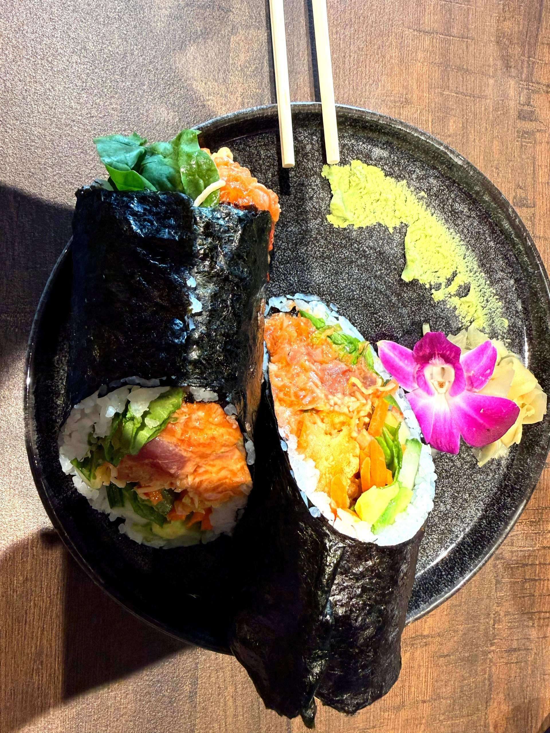 WAVE Sushi burrito on black plate with chopsticks and garnish
